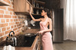 © LIGHTFIELD STUDIOS - side view of sexy young woman in apron holding frying pan while cooking at kitchen