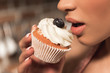 © LIGHTFIELD STUDIOS - close-up partial view of sensual young woman eating delicious cupcake