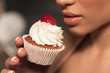 © LIGHTFIELD STUDIOS - cropped shot of sensual young woman holding delicious cupcake near lips