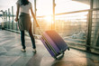 © Take Production - Young woman pulling suitcase in  airport terminal. Copy space