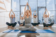 © LIGHTFIELD STUDIOS - group of senior people practicing yoga with instructor in lotus pose on mats in studio