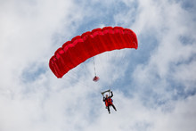 Parachuter Descending With A Red Parachute