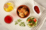 Fototapeta Kuchnia - Fried meat cutlets in ceramic soup bowl, tomatoes, ceramic sauce boat with tomato sauce, branch of fresh parsley, glass of wine, kitchen towel and glass bottle with sunflower oil on grey wooden boards