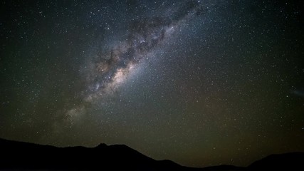 Wall Mural - Time lapse looking up at the Milky Way from a misty valley surrounded by mountains, viewed from the southern hemisphere in Australia.