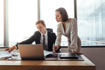 Wall Mural - Business colleagues over viewing contract papers in office