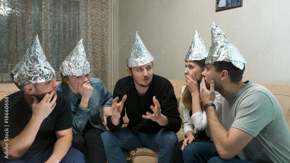Group of people with foil on their heads discussing conspiracy theories. Friends with foil on their heads. You know, so they can't read your mind