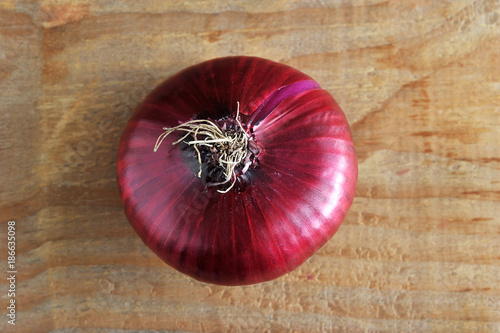 Fotomural a whole onion in red on rough wooden background