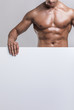 © cristovao31 - Muscular man holding a blank board on grey background