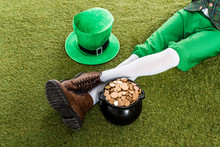 Cropped View Of Leprechaun With Hat And Pot Of Gold Sitting On Green Grass