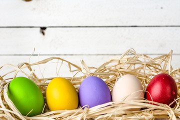 Easter background, seasonal colorful painted easter eggs on wooden white boards