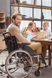 © LIGHTFIELD STUDIOS - father on wheelchair teaching children at home and looking at camera
