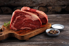 Raw Fresh Meat Ribeye Steak, Seasoning And Meat Fork On Dark Background