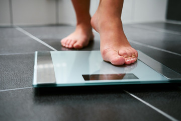 female bare feet with weight scale in the bathroom