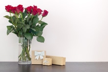 Beautiful Red Roses In A Vase And Gift Glitter Boxes On A Wooden Surface