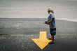 © Cavan Images - Side view of boy with tablet computer looking up while standing by arrow symbol on road