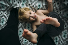 Overhead Portrait Of Cheerful Boy Playing On Bed At Home