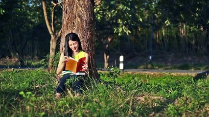 Sticker - woman sitting on grass and reading a book in the garden