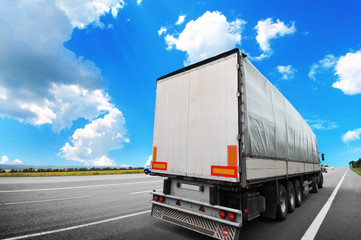 Wall Mural - Semi truck with a white trailer on the countryside road against sky with clouds