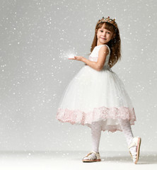 Young little girl model in the white communion  winter dress stands in gold crown with expensive gems