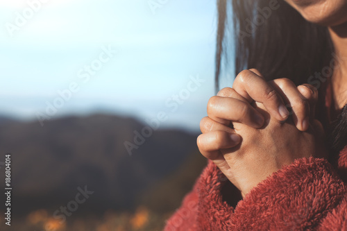 Fotomural Woman hands folded in prayer in beautiful nature background with sunlight in vin