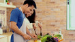 © Kittiphat - Young Asian Couple having fun Preparing Food, vegetable and salad in the Kitchen