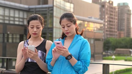 Wall Mural - two young women jogger using smartphone