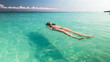 © FarfallaPhotographie - Full body view of young woman floating on back in turquoise tropical sea