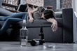 After drinking. Sleepy drunk young woman lying on the sofa and sleeping with empty bottles standing on the floor in front of her