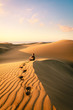 Man sitting and relaxing on sand dunes by the sunrise, in Maspalomas on Gran Canaria.