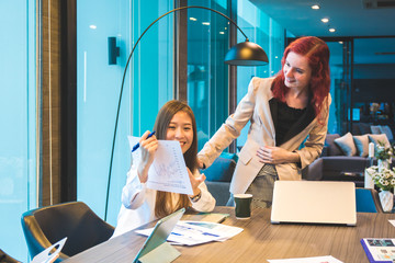 Wall Mural - Multi ethnic team of women discussing or having a brainstorm about startup plans or business ideas in modern office with city scape background.