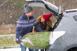 © pikselstock - Young couple with Christmas tree into car boot