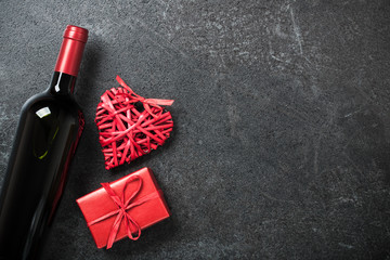 Wall Mural - Red wine bottle, gift box and wicker heart on black background