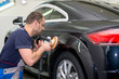 © zhekkka - A man polishes a black car with a polisher