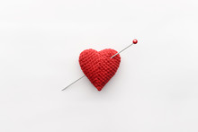 Knitted Heart Of Red Thread With Inserted Knitting Needle On White Background
