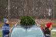 © pikselstock - Couple with their christmas tree on roof of the car
