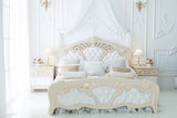 Fototapeta Uliczki - Bed in a large beautiful bedroom in the style of rococo.