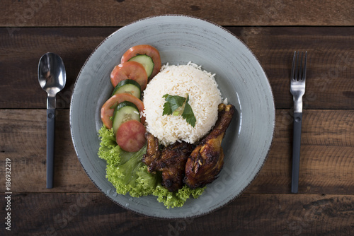 Fotografía Popular Malaysian dish Nasi Ayam or chicken rice with baked chicken pieces, tomato, cucumber and salad