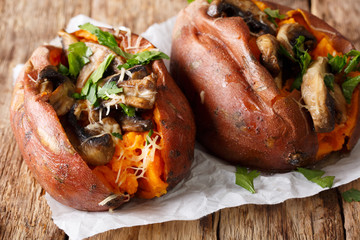 Organic baked sweet potato with mushrooms, herbs and cheese close-up on parchment. horizontal