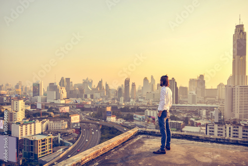 Cuadros en Lienzo Western businessman looking at the city at sunset