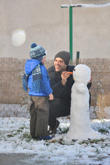 Wall Mural - Father and son make a snowman in backyard. Happy family play on snow