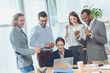 © LIGHTFIELD STUDIOS - business team standing against sitting woman at office space