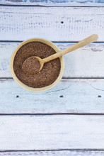 Wooden Spoon And Bowl Of Organic Linseed On Light Blue Wood