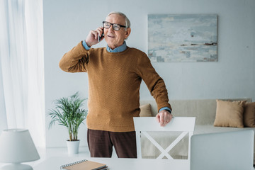 Wall Mural - Elder smiling man working in office and making phone call