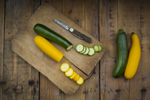 Whole And Sliced Yellow And Green Zucchini On Wood