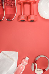 Sports equipment with shoes, dumbbells, ball and headphones isolated on red