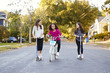 © Monkey Business - Three pre-teen girls riding in street on scooters and a bike