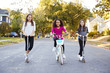 © Monkey Business - Three pre-teen girls on scooters and bike looking to camera