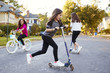 © Monkey Business - Girls playing in the street on scooters and a bike, close up