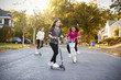 © Monkey Business - Three girls riding down the street on scooters and a bike