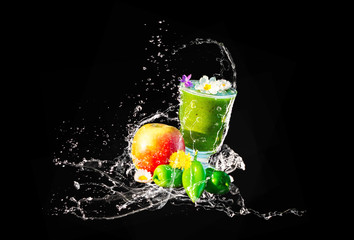 Wall Mural - Grüner Smoothie mit essbaren Blüten und Früchten, Wasserspritzer, isoliert auf schwarz